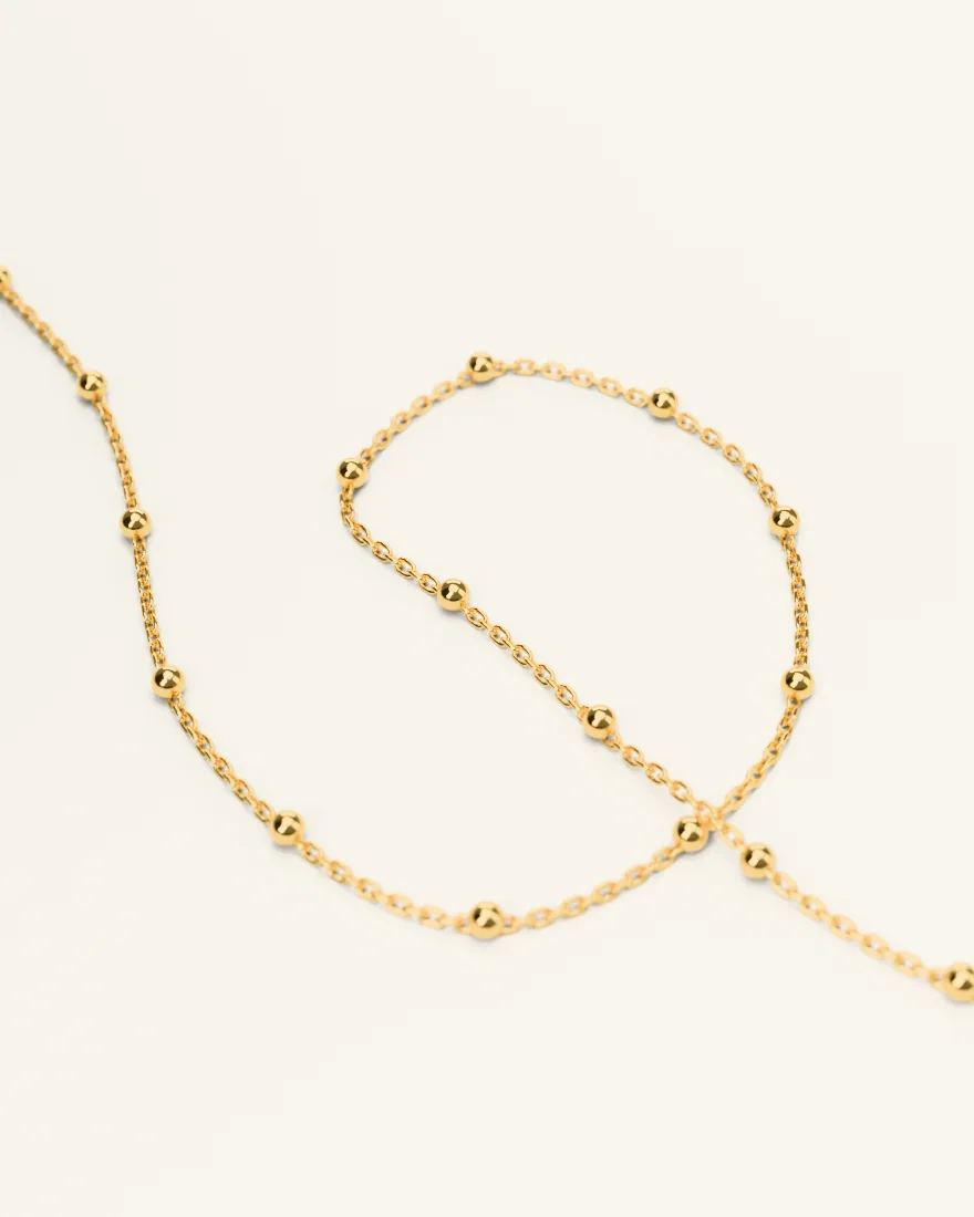 Fine gold chain with small gold beads, curled into a loop